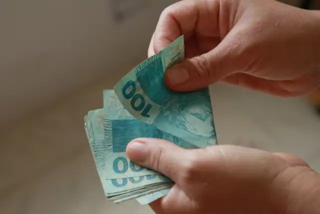 mãos contando dinheiro em notas de 100 reais - dicas para ganhar dinheiro